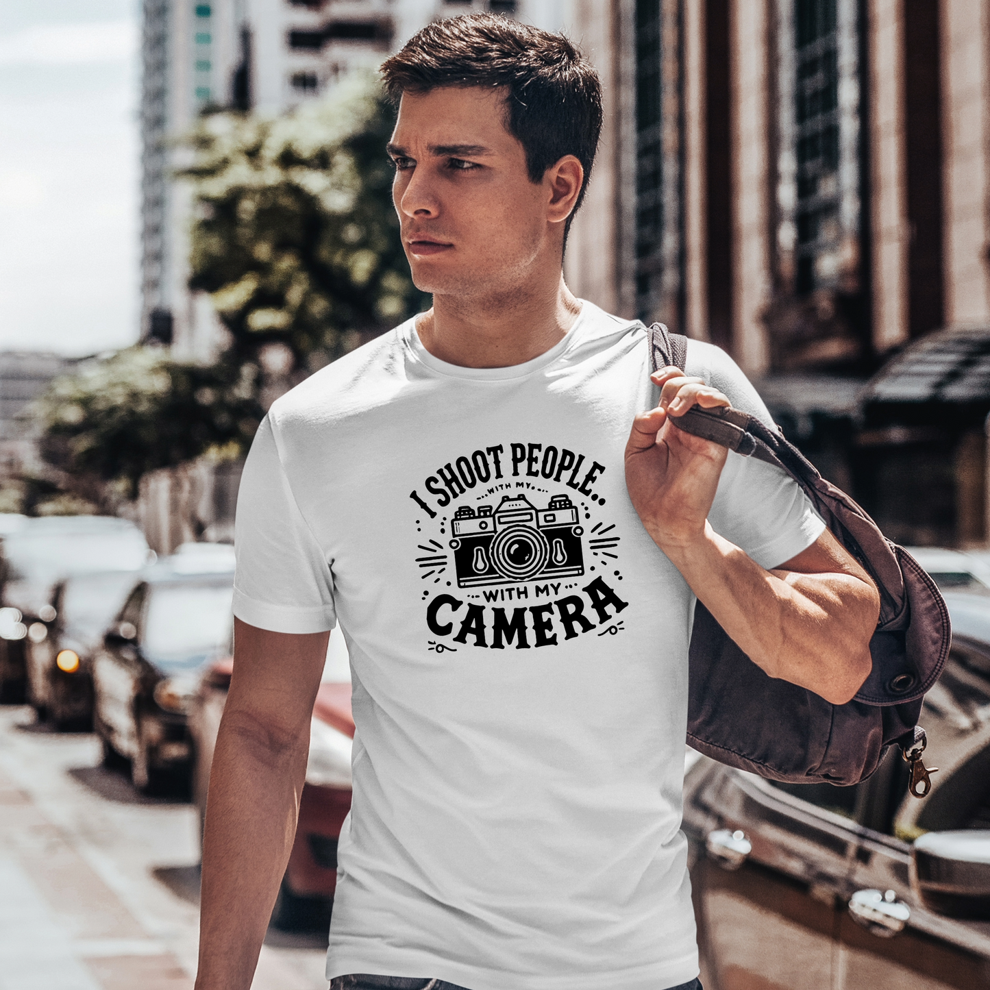 (Indossata Uomo, città): Uomo che indossa la t-shirt bianca "I Shoot People with My Camera" mentre cammina per la città con una borsa a tracolla. Design con macchina fotografica vintage e scritta ironica per fotografi.