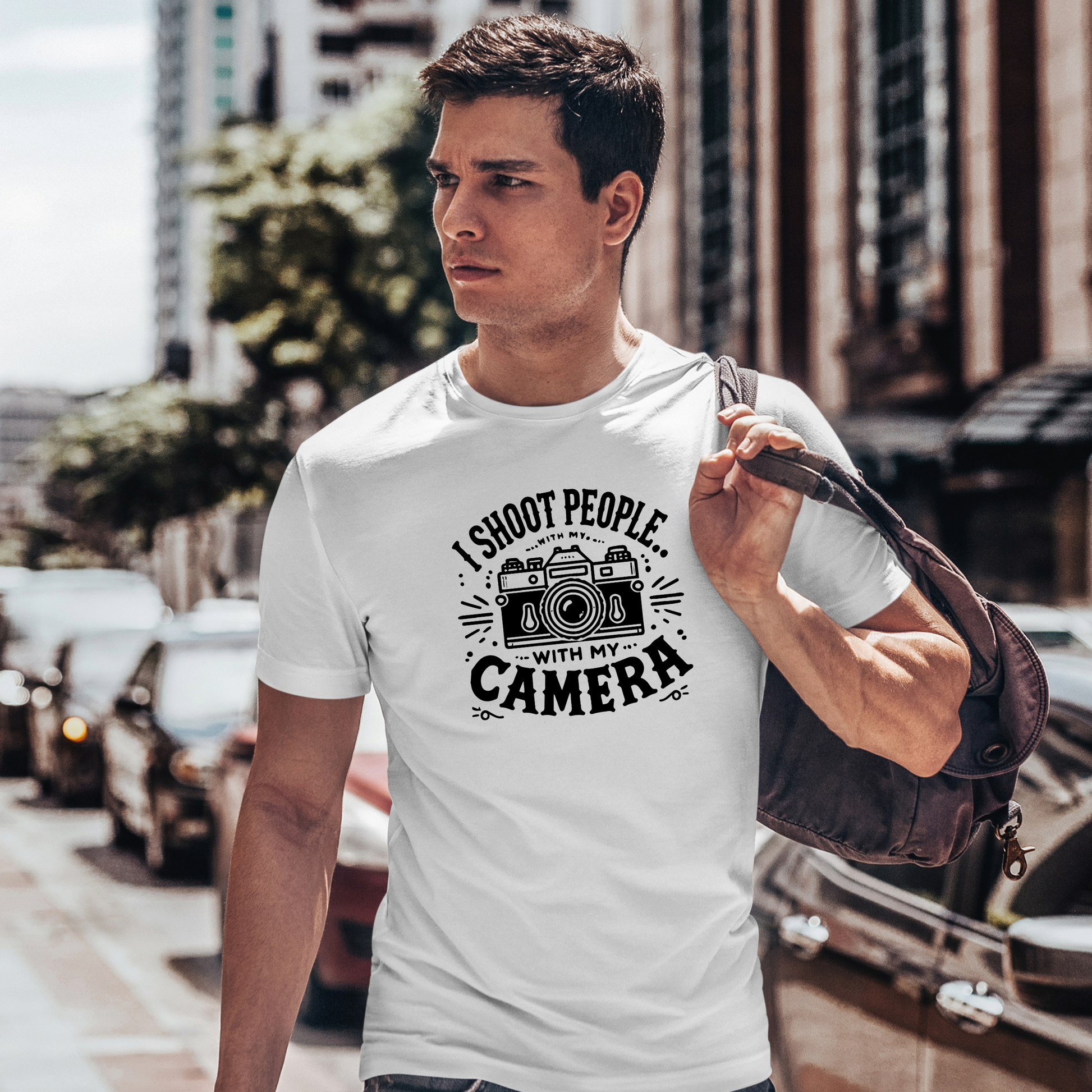 (Indossata Uomo, città): Uomo che indossa la t-shirt bianca "I Shoot People with My Camera" mentre cammina per la città con una borsa a tracolla. Design con macchina fotografica vintage e scritta ironica per fotografi.