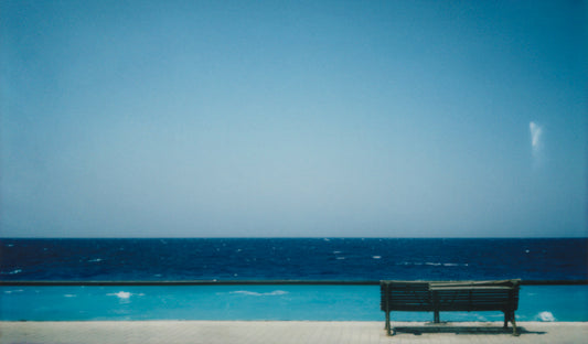 "Stampa Polaroid – Panchina fronte mare con piscina a sfioro, atmosfera minimalista e contemplativa."