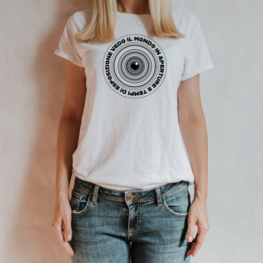 T-shirt bianca indossata
"T-shirt bianca 'Aperture & Exposure' con design di un obiettivo e frase sulla fotografia, indossata da una donna con jeans, su sfondo neutro."