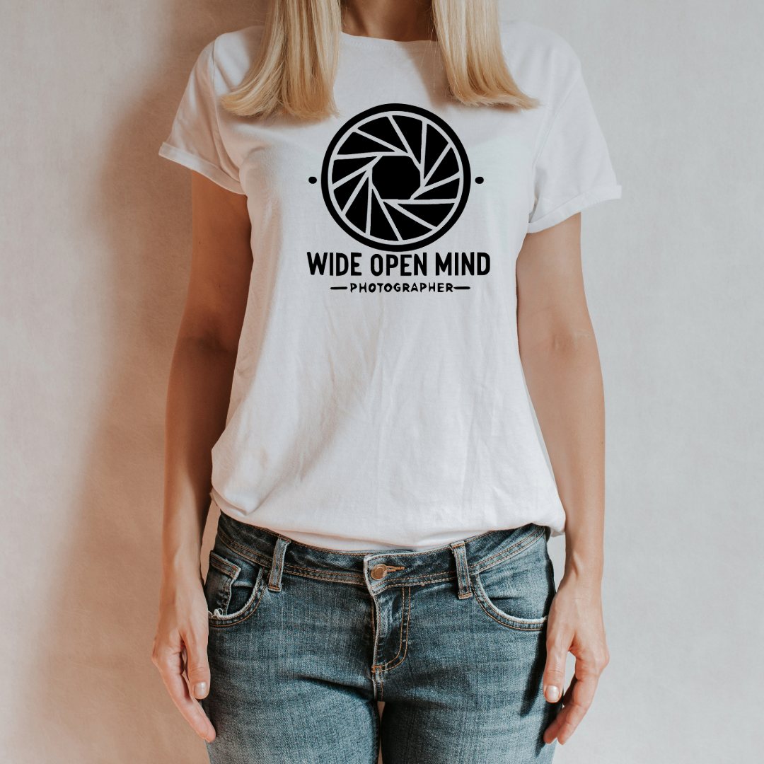 -shirt bianca "Wide Open Mind" indossata da una donna, con design minimalista ispirato al diaframma di una fotocamera.